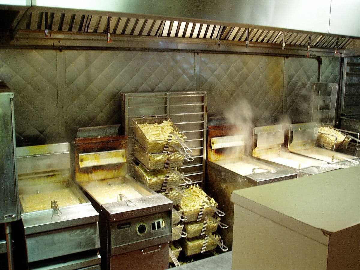 Bank of commercial fryers cooking fries in a restaurant kitchen