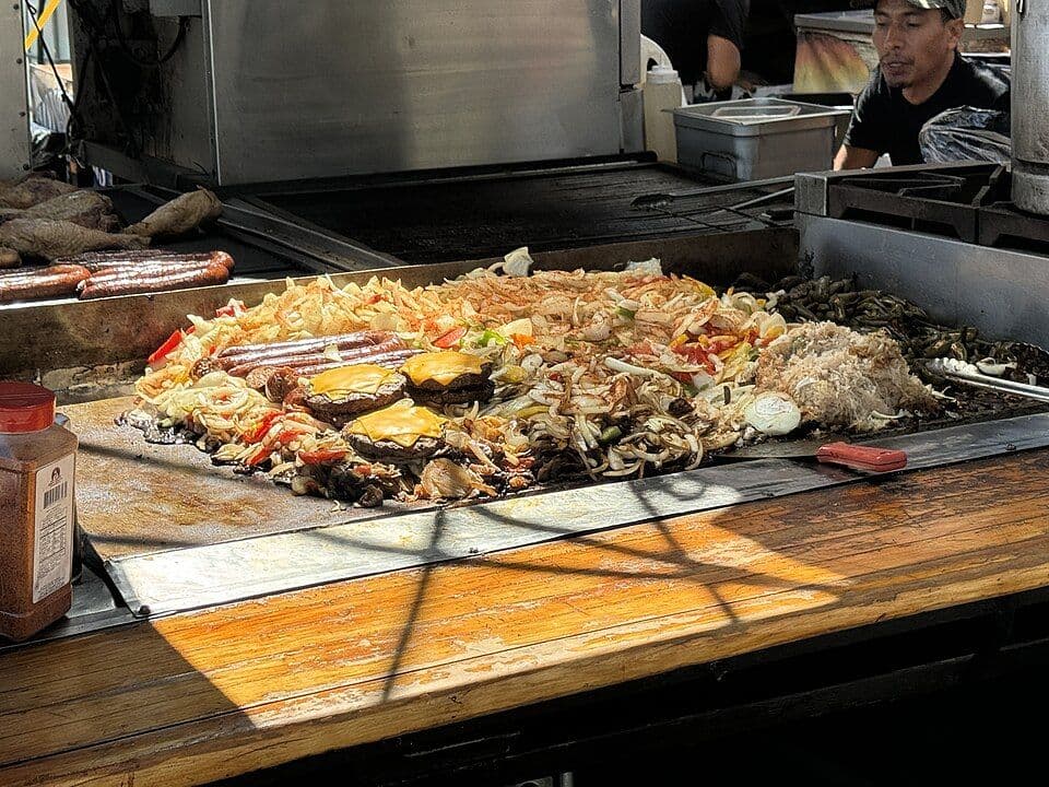 Food cooking on a large commercial flat-top griddle